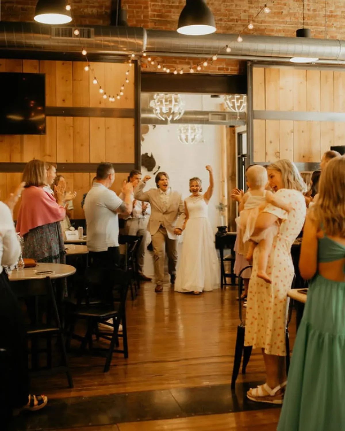 Newlyweds entering their reception as guests cheer