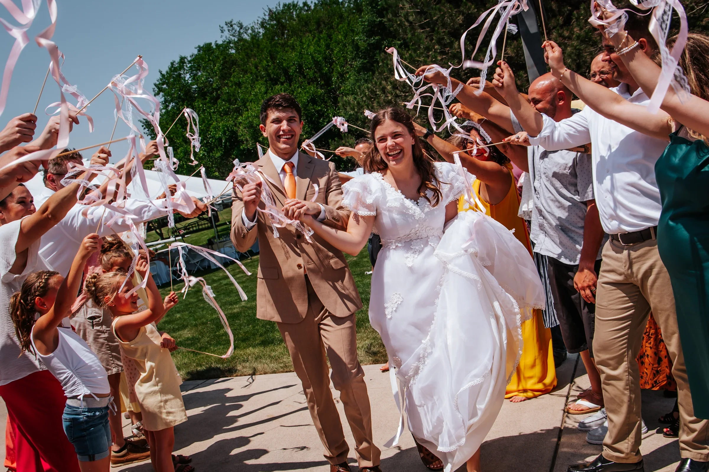 Newlyweds walking beneath ribbons held by their wedding guests